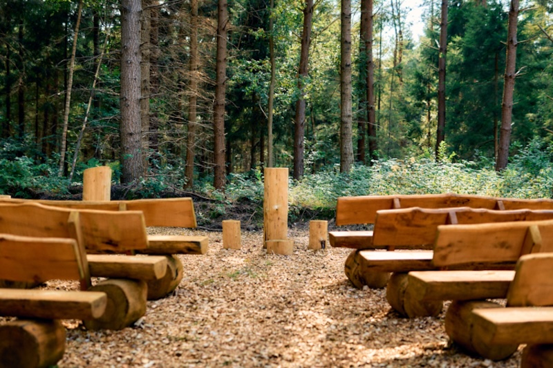 Andachtsplatz mit Holzbänken im Wald.